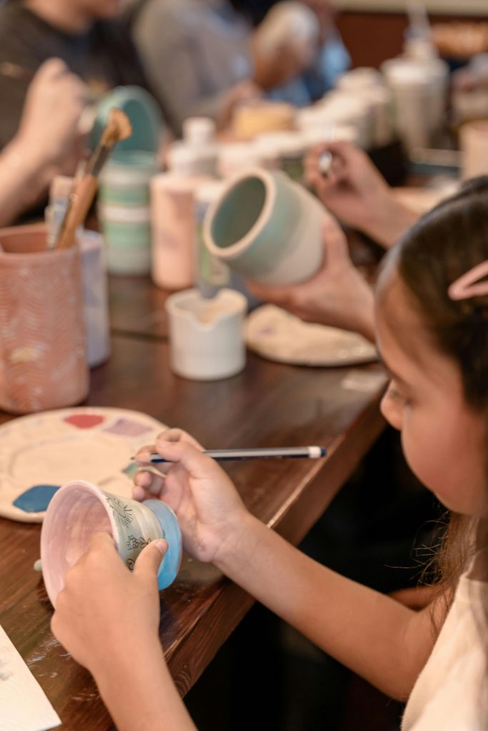Children creatively paint ceramics in a pottery workshop, fostering teamwork and artistic skills.