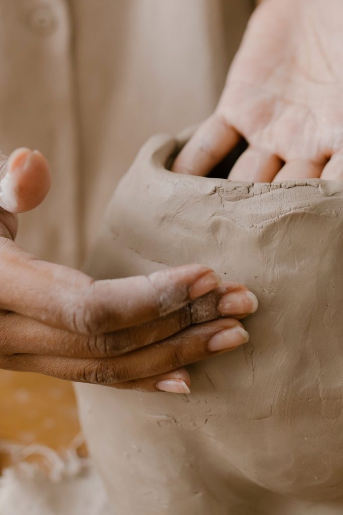 Artisan hands sculpting a clay pot in a detailed close-up in a pottery workshop.