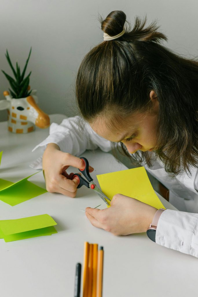 Focused woman cutting colorful paper in a creative indoor setting.