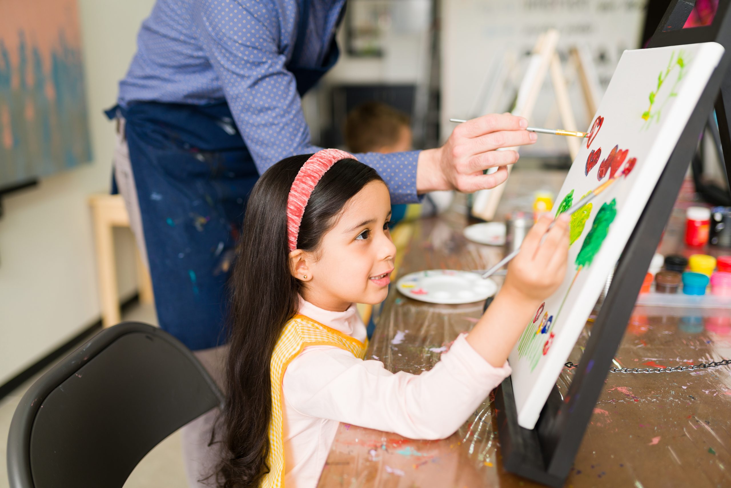profile of a little girl smiling while painting a landscape in art school